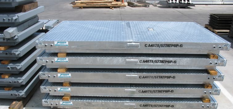 Metal access hatches stacked in the Jensen yard